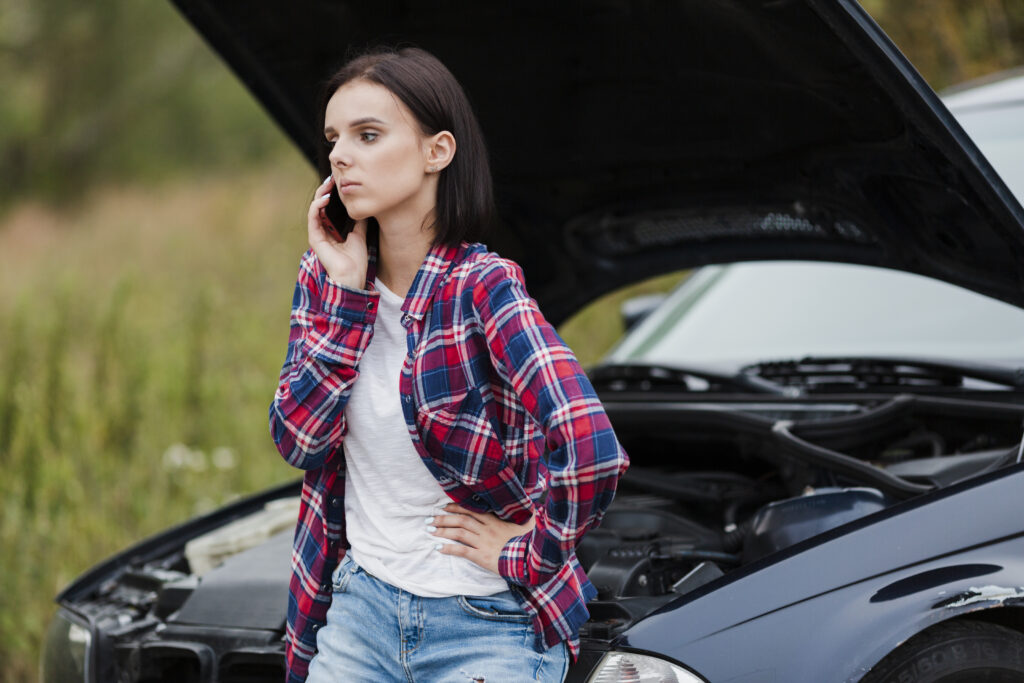 In this picture it shows the woman is very upset with the issue with her car along the road and calling for mechanic to resolve the issue.